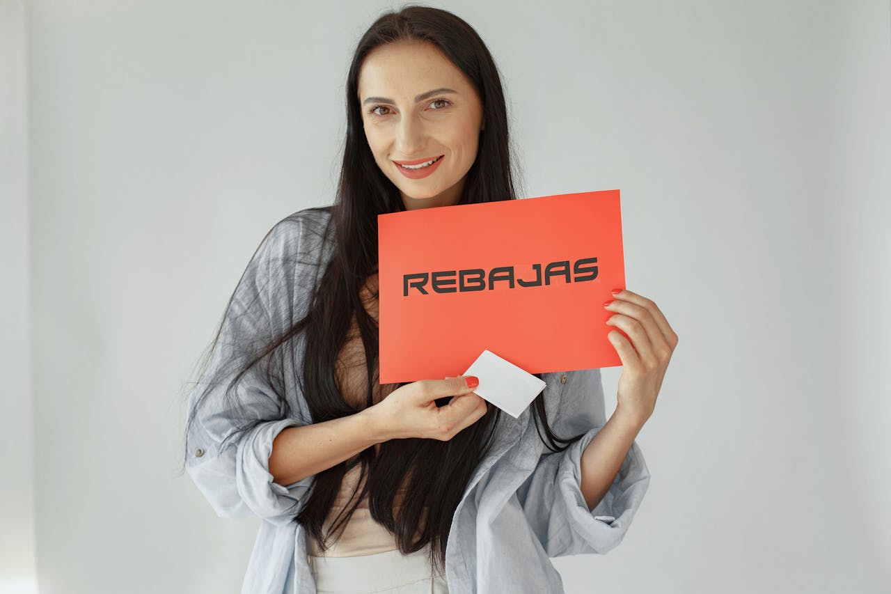 Smiling woman holds a red REBajas sign, promoting sales and discounts.
